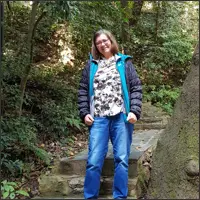 The author stands beside a rocky path surrounded by dense woodland on Yuelu Mountain.