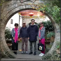 Four friends pose together inside a circular stone gateway in Jinggang Ancient Town.