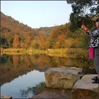 Autumn-covered hills and trees are reflected in the calm water of a lake at Taohualing Park.