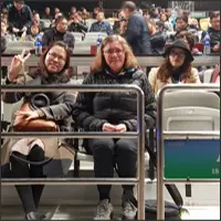 Renee seated in the front row beside another spectator, with the audience behind them.