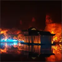 Orange light and projected flames stretching across the water stage.