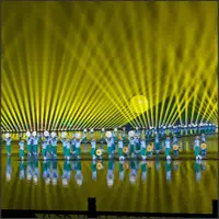 Dancers in blue and white costumes beneath a fan of golden light beams.