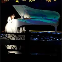 Pianist at a white grand piano on the dark water stage.