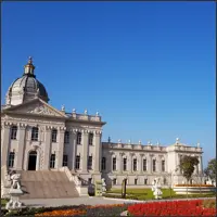 European-style palace square with a large statue and formal flower beds
