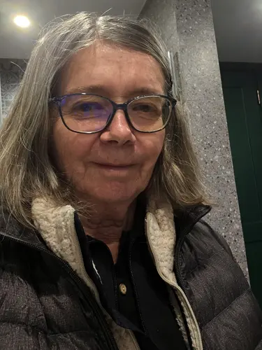 Woman wearing multiple layers of clothing on a sunny but cool day in Kunming.