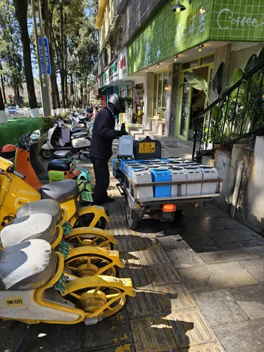 Man replacing charged batteries in rental scooters and bikes from a cart filled with battery packs.