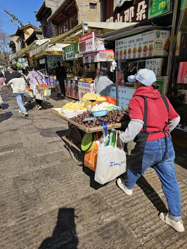 Several street vendors quickly pushing their carts away and running from officials in a Chinese city street.