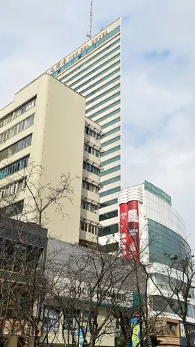 Back view of the New Era Hotel in Kunming, showing a broad striped façade that appears almost completely flat from this angle.