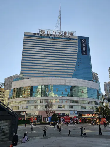 Front view of the New Era Hotel in Kunming, a large striped building with a curved glass base, appearing visually flat from this perspective.