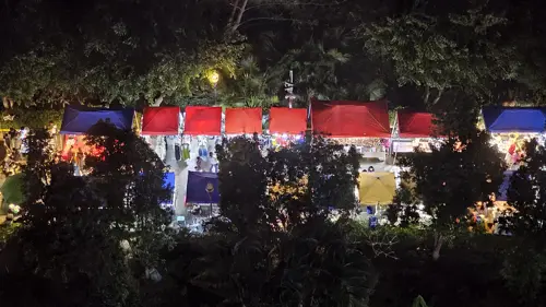 Night view of a long riverside market in Jinghong with brightly lit stalls and crowds of people