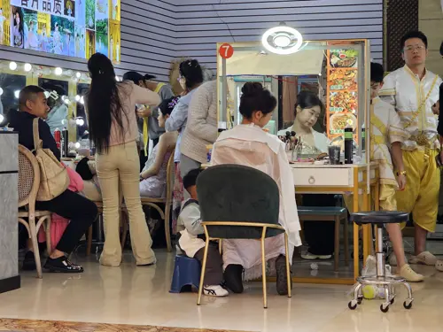 People preparing costumes and makeup in a shop offering traditional and cosplay outfits in Jinghong