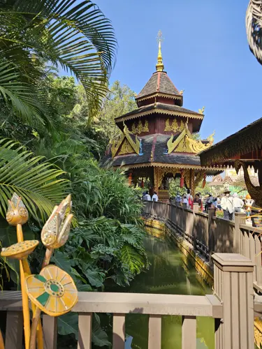 Traditional Dai-style pavilion and covered walkway over water in Manting Park surrounded by tropical greenery
