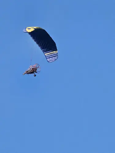 Small paraglider flying in a clear blue sky