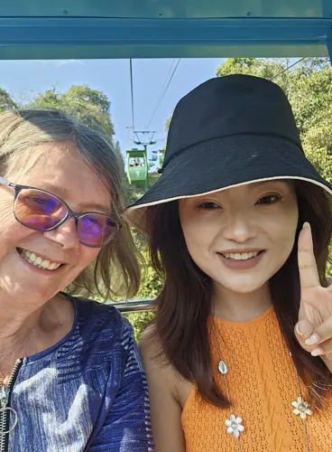 Two women smiling inside a gondola cabin above the forest in Wild Elephant Valley