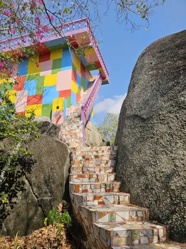 Staircase and viewing platform with colorful mosaic tiles at Wat Khao Hin ThoenMosaic-tiled staircase leading to a colourful viewing platform beside massive boulders at Wat Khao Hin Thoen