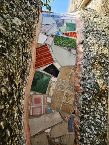 Mosaic tiles set into a narrow crack between large rocks