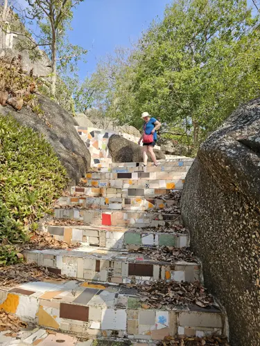 Woman walking down mosaic-tiled steps between large rocks