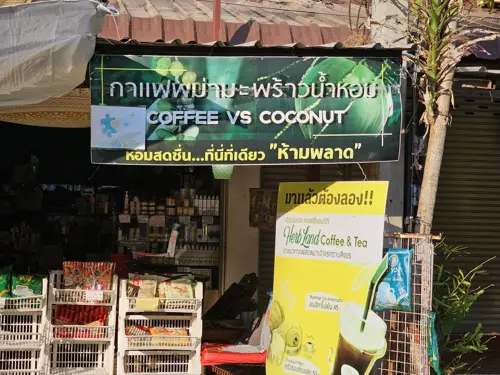 Small roadside shop with a sign reading 'Coffee vs Coconut'
